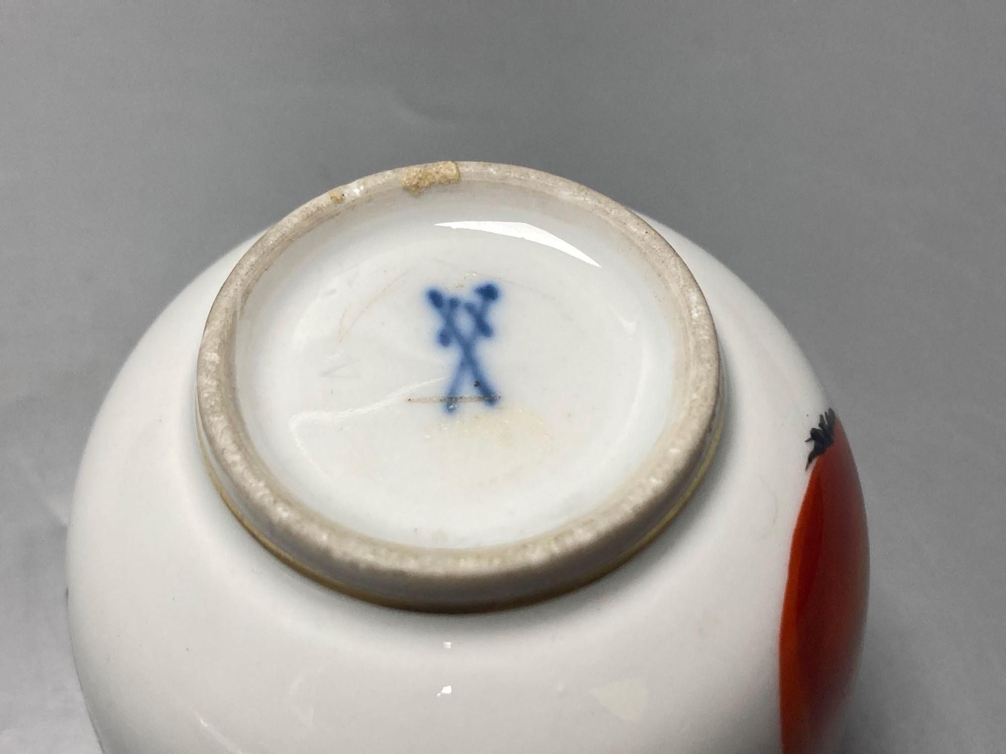 A Meissen cup and saucer, factory seconds, decorated with fruit and butterflies and lined with gilt